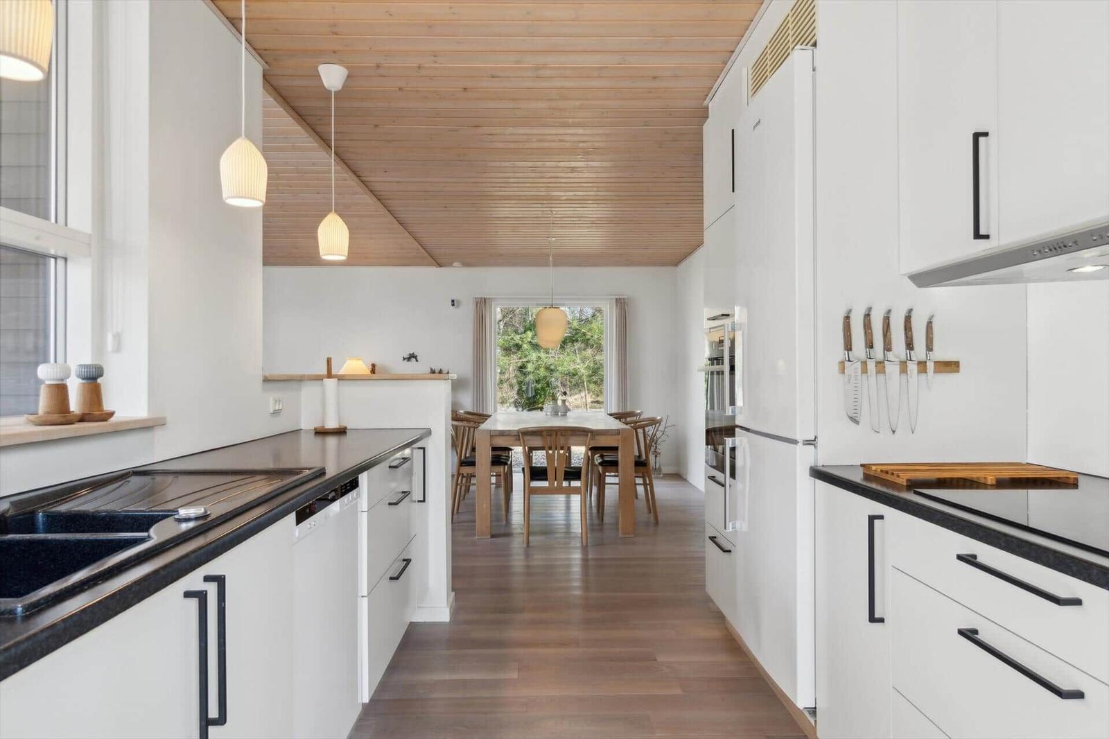 Küche mit Essbereich, Holzdecke und modernen Schränken.
