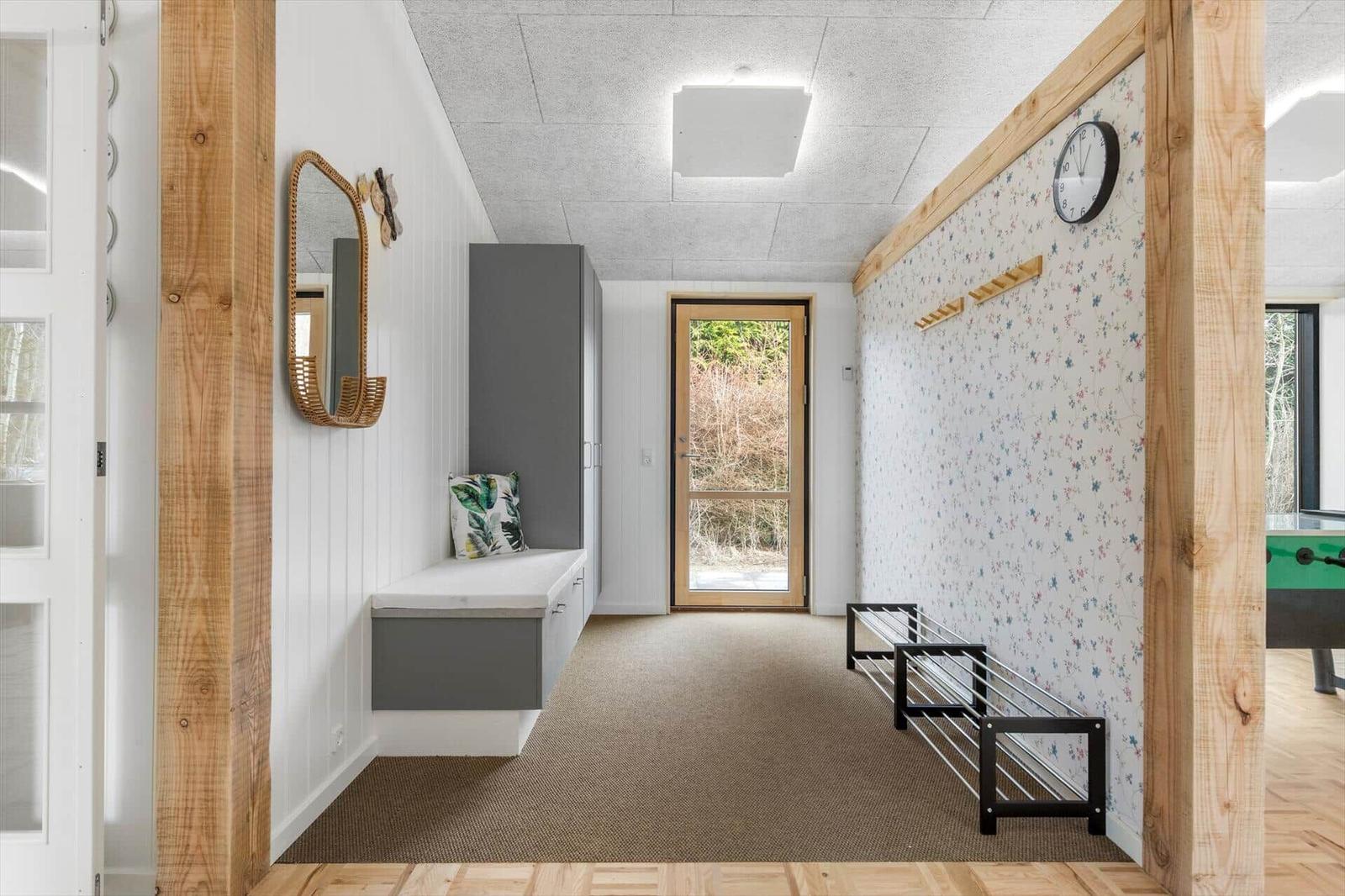 Hallway with coat rack, mirror, and door to outdoor area.