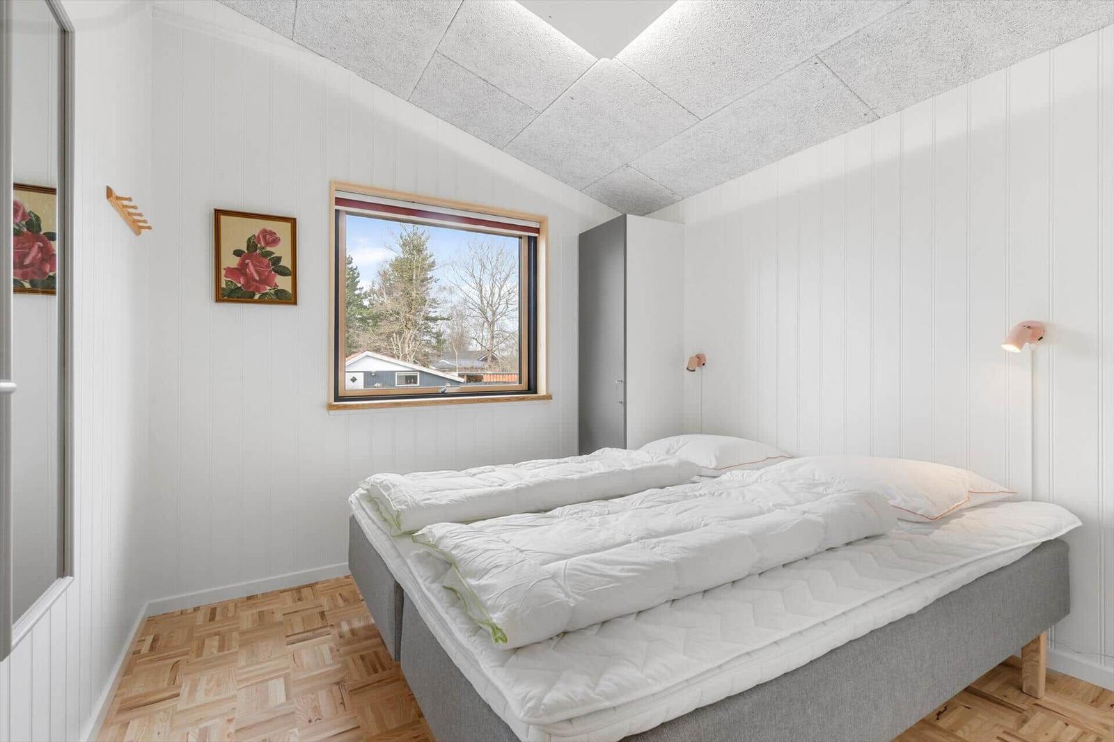 Bedroom with bed, window, and wooden floor.