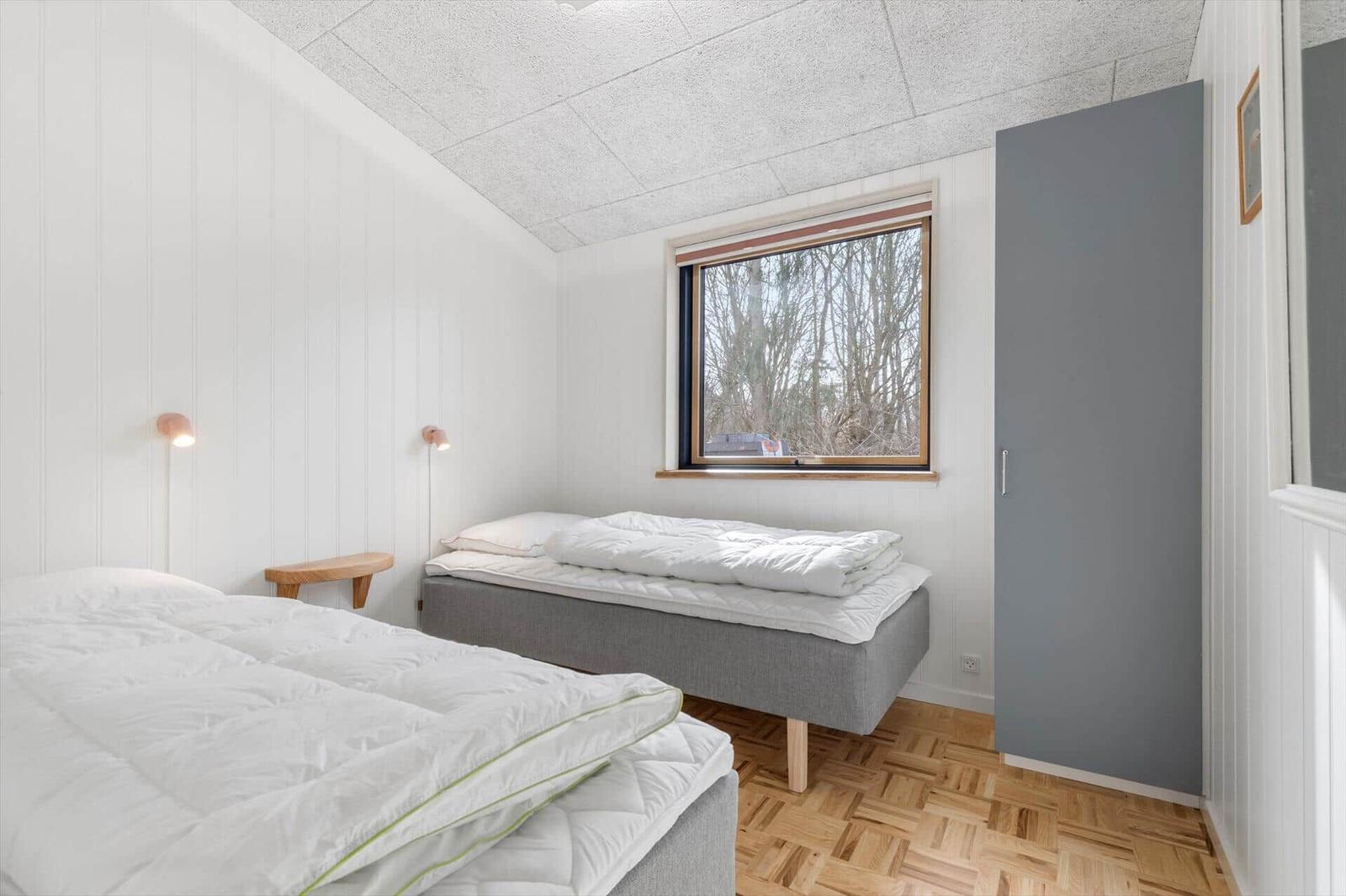 Room with two beds, window and wooden floor