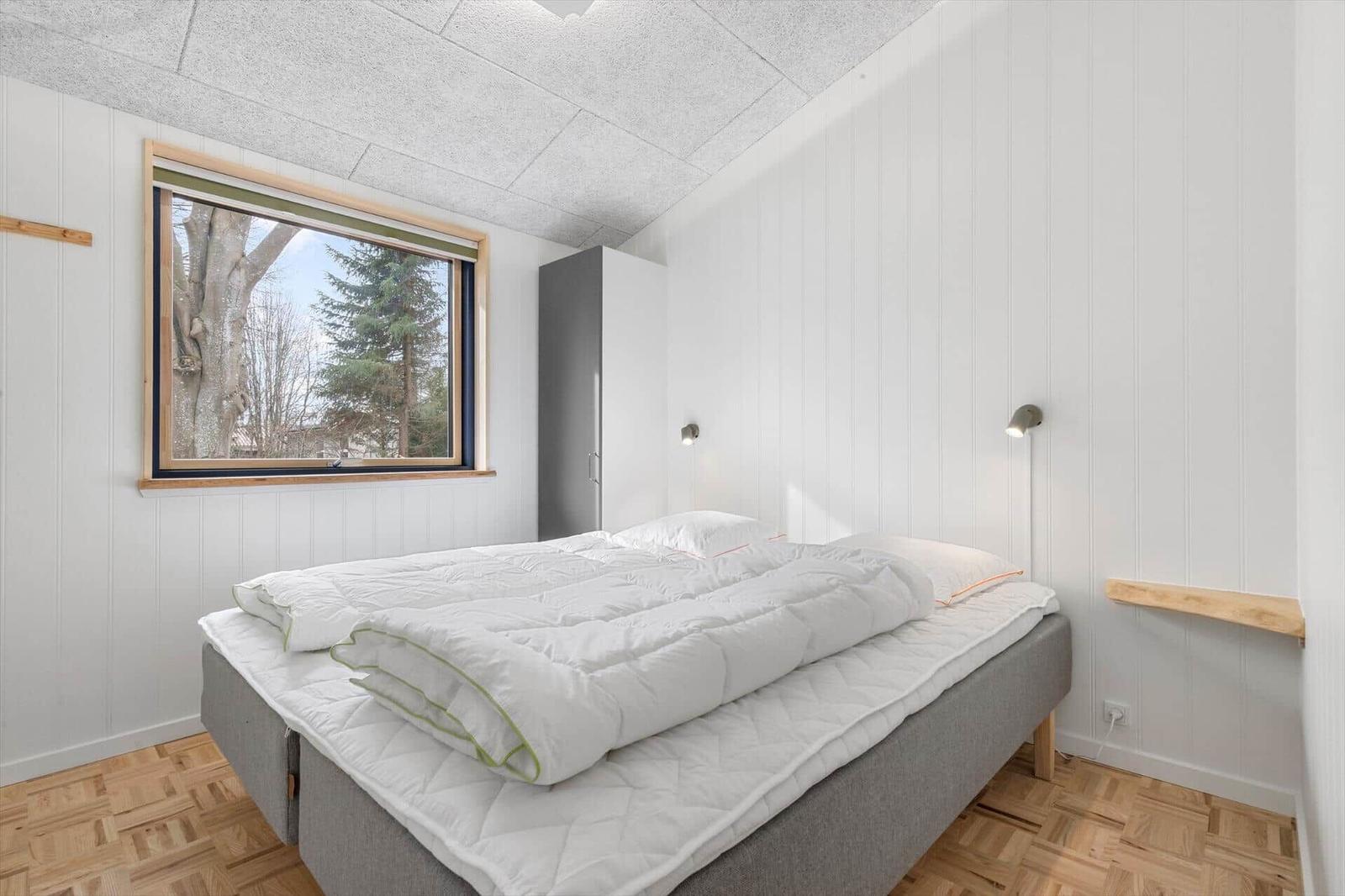 Bedroom with bed, window, and wardrobe.