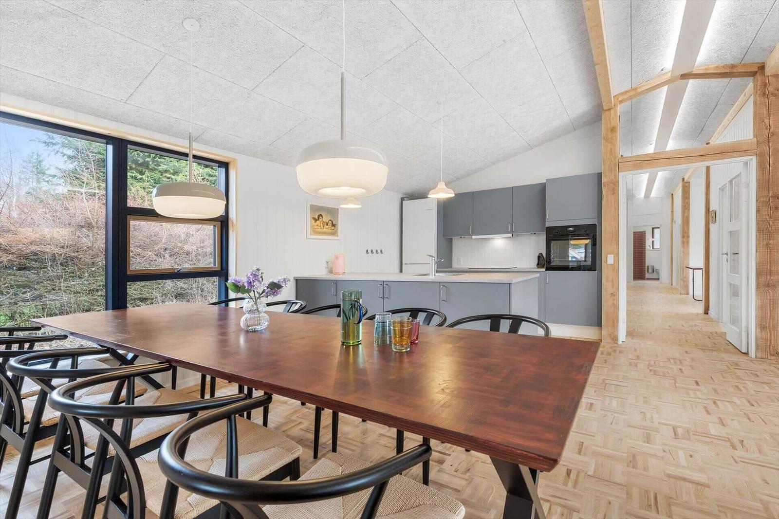 Dining area with table, chairs, and kitchen area in the background.