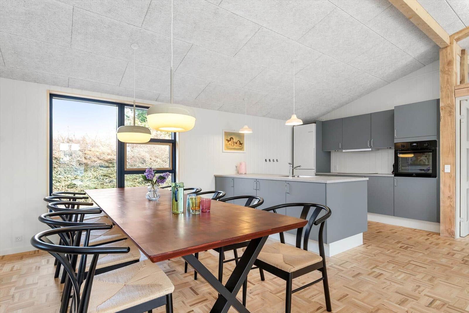 Kitchen and dining area with wooden floor, gray cabinets, and large window.