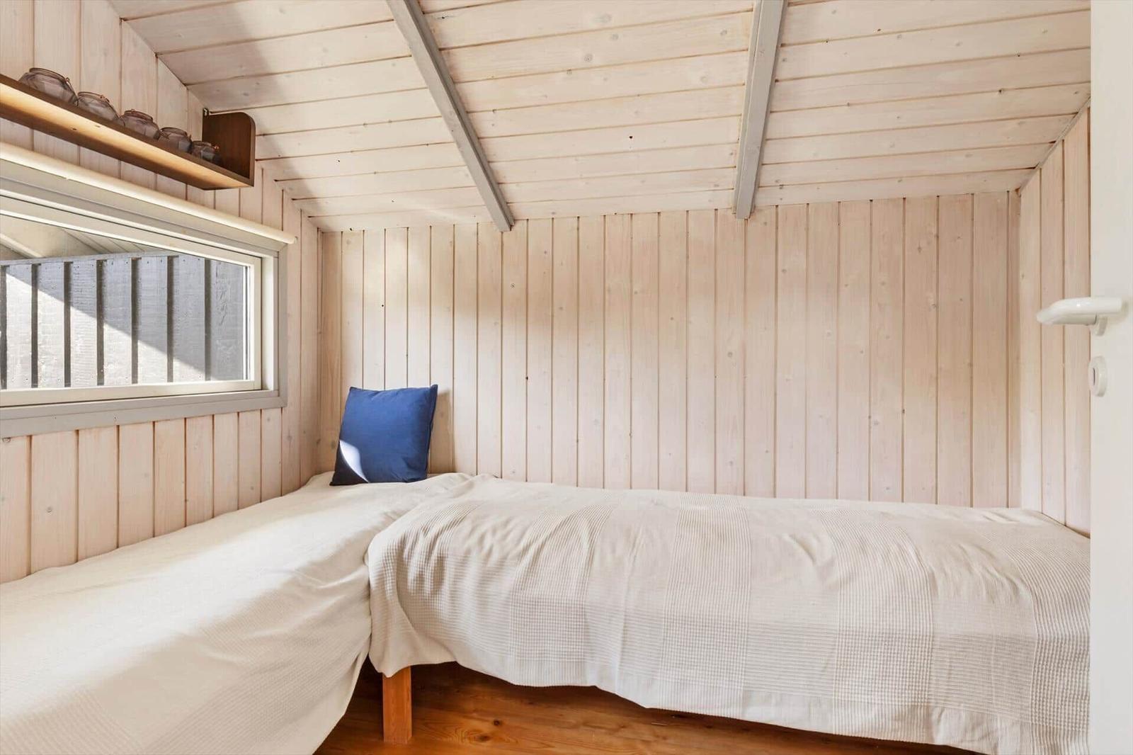 A bedroom with wooden walls, bed, and window.