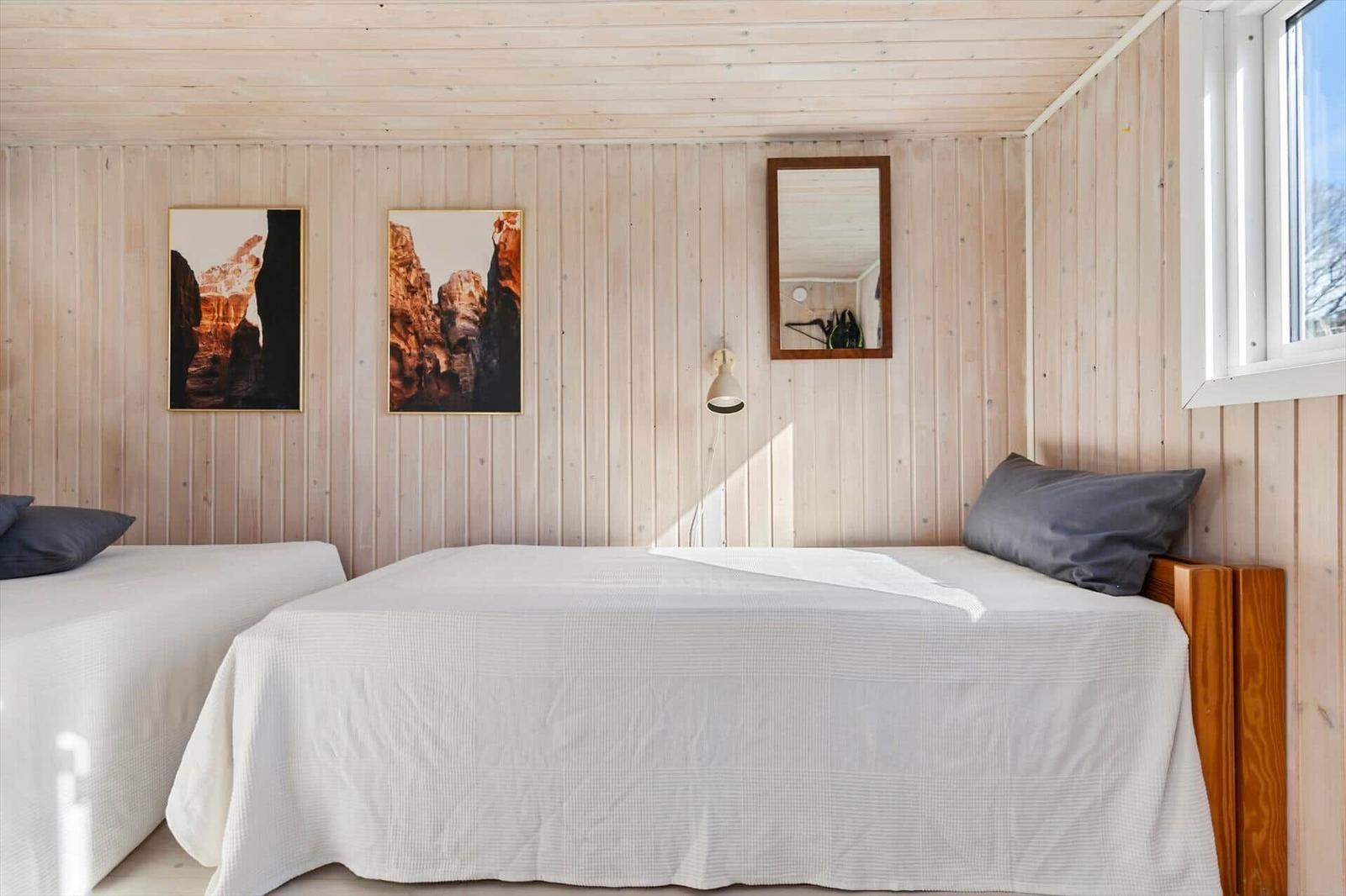 Two beds with white bedcovers, wooden walls and window