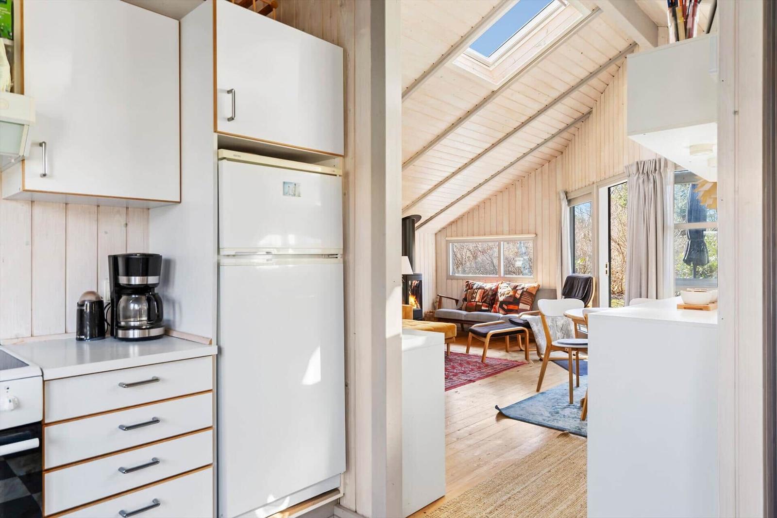 Kitchen with refrigerator and coffee maker. Living area with sofa, fireplace, and skylight.