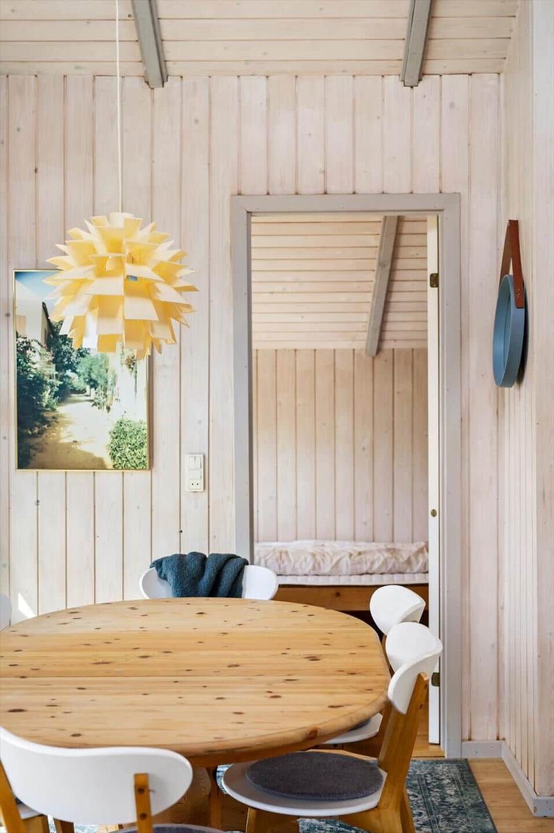 Dining area with round table and white chairs. Behind door is sleeping area with mattress.