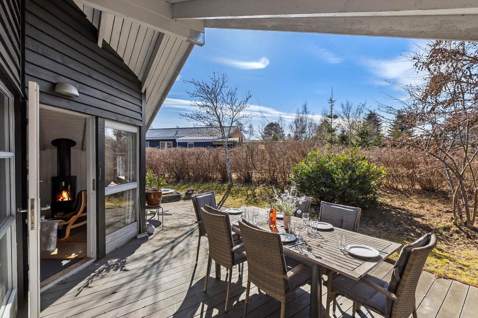 Deck with table and chairs, view of garden and sky