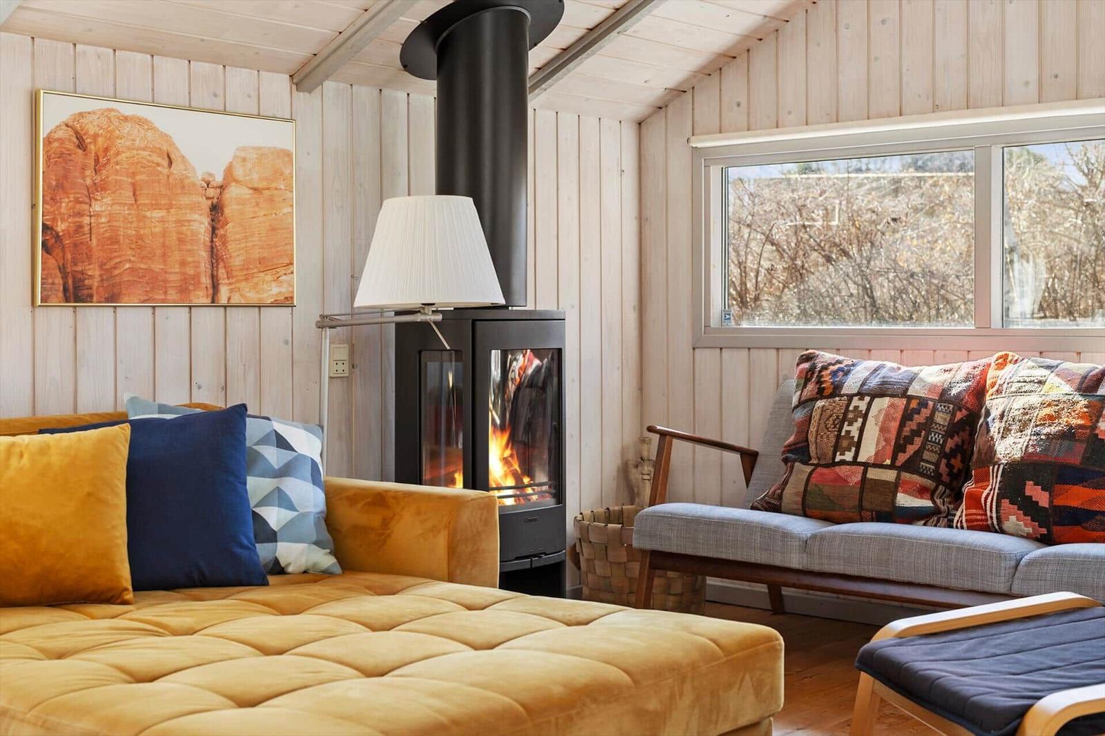A room with fireplace, sofa, and window. Wall art and cushions are visible.