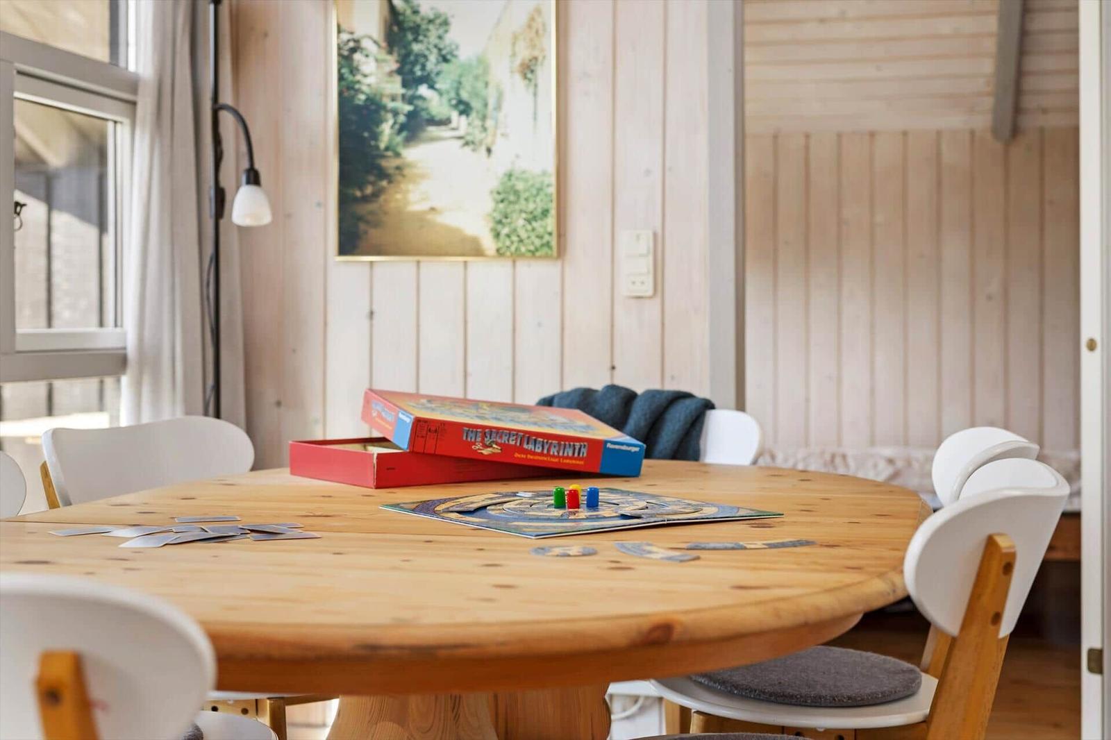 Round wooden table with toys and chairs in a room with wooden walls.