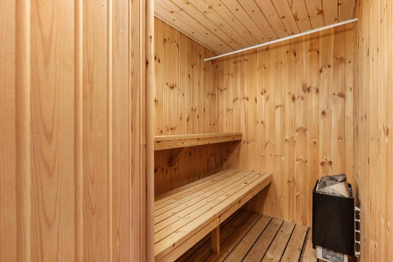 Sauna with wooden walls, bench, and floor. Wooden box with firewood.