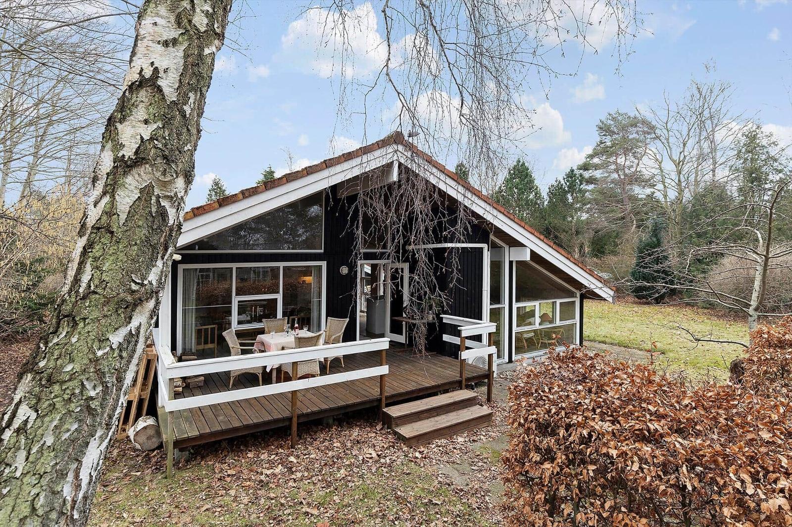 Wooden house with terrace and large window area in the forest