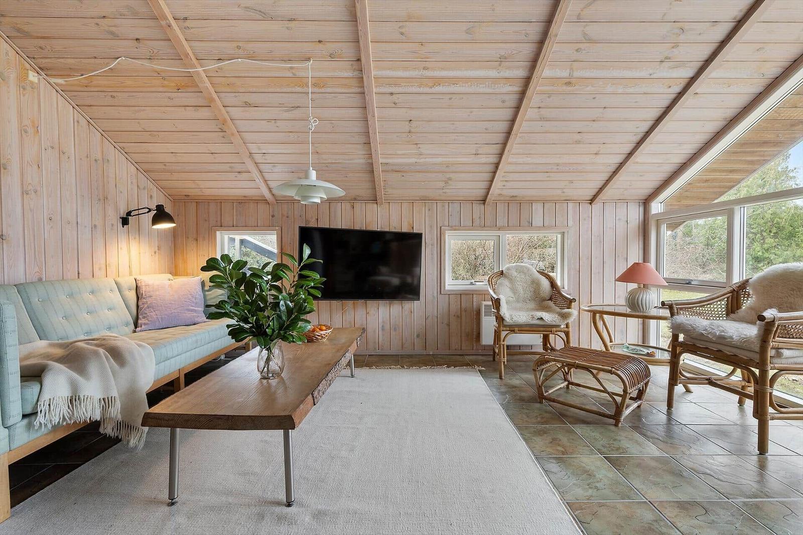 Living room with wooden walls, sofa, TV, and seating areas.