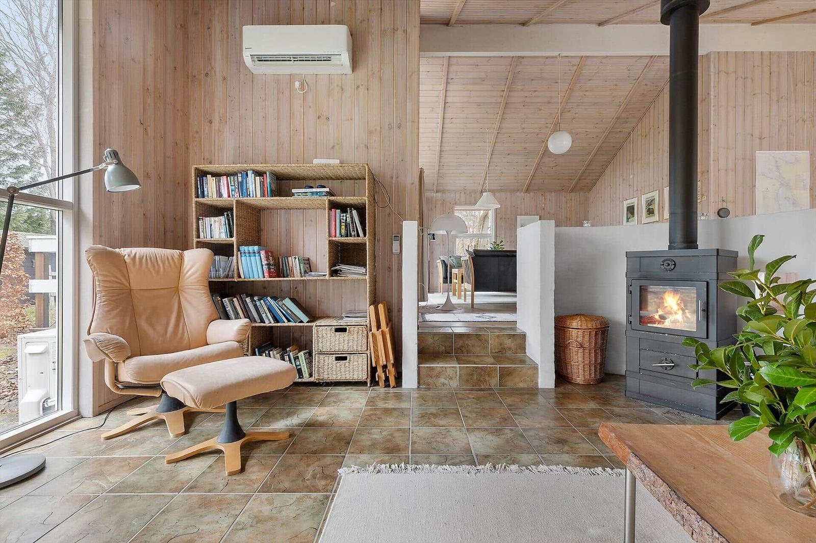 Living room with wood wall, armchair, fireplace, and bookcase.
