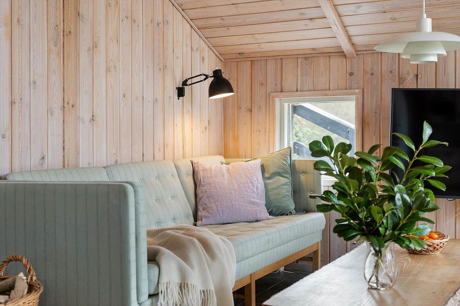Living room with sofa, plant, and TV on wood wall