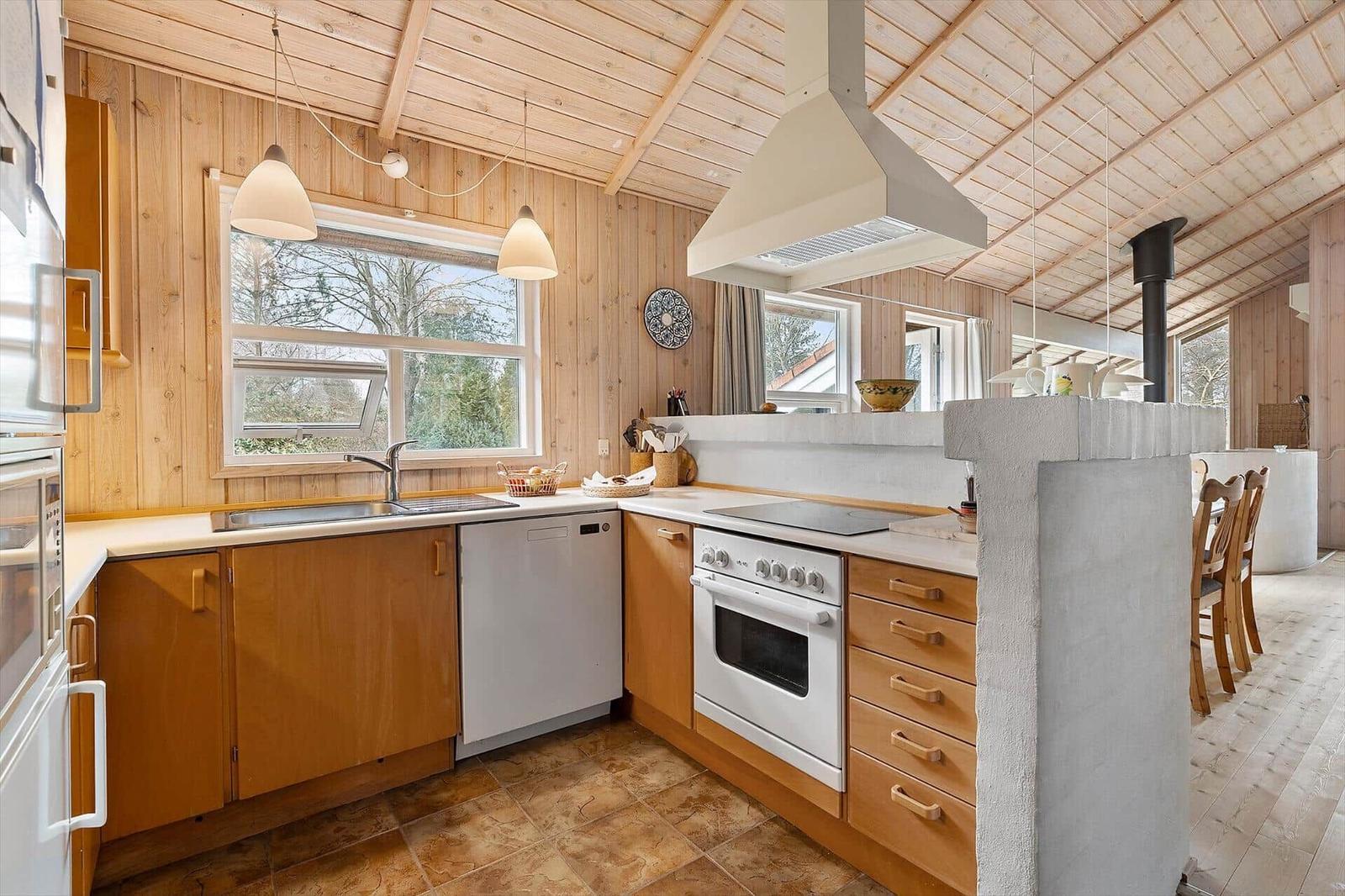 Kitchen with wooden walls, white appliances, and stone island