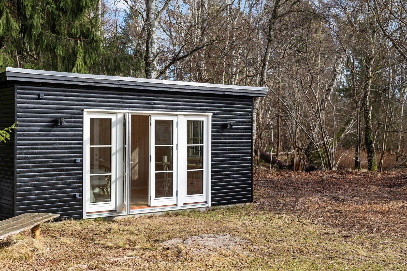 Black wooden house with white glass doors in the forest
