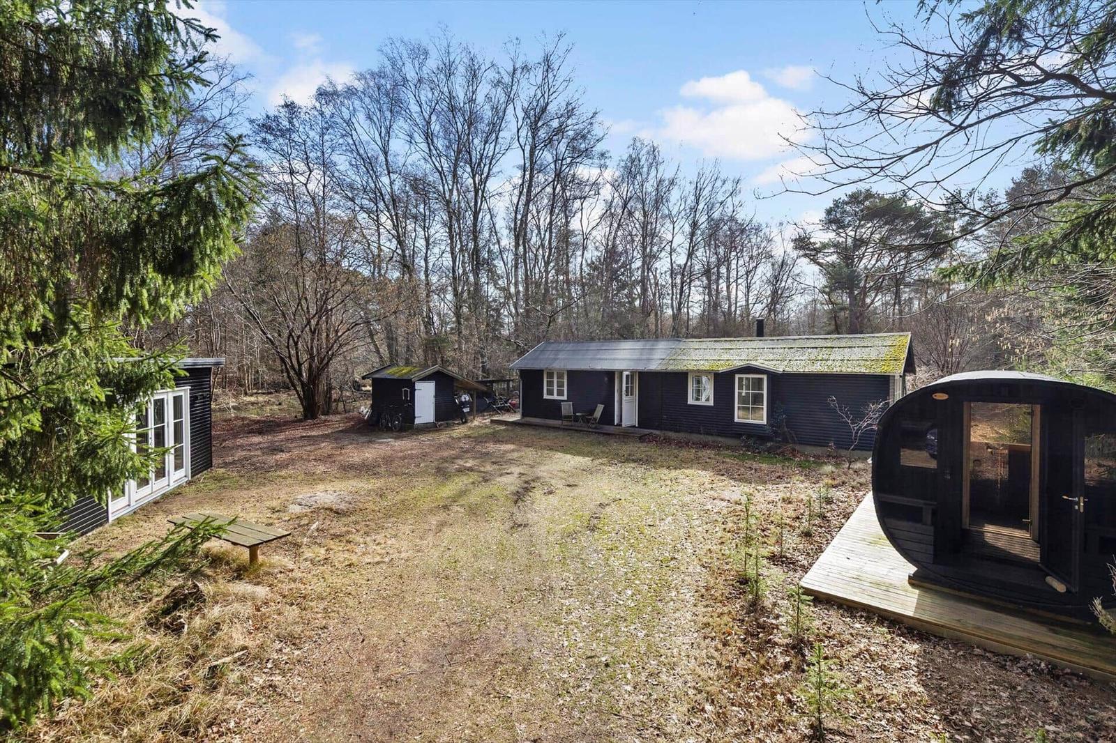 Wooden house with garden, sauna, and barbecue area in the forest.
