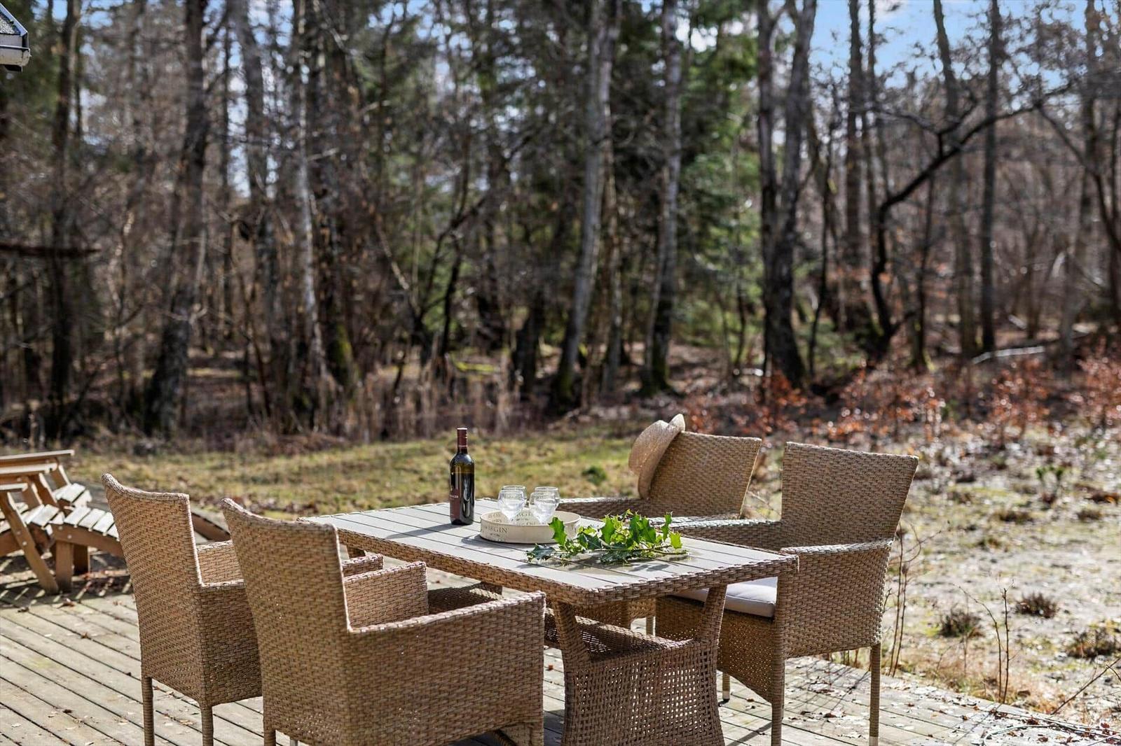 Wooden terrace with dining table and chairs in the woods