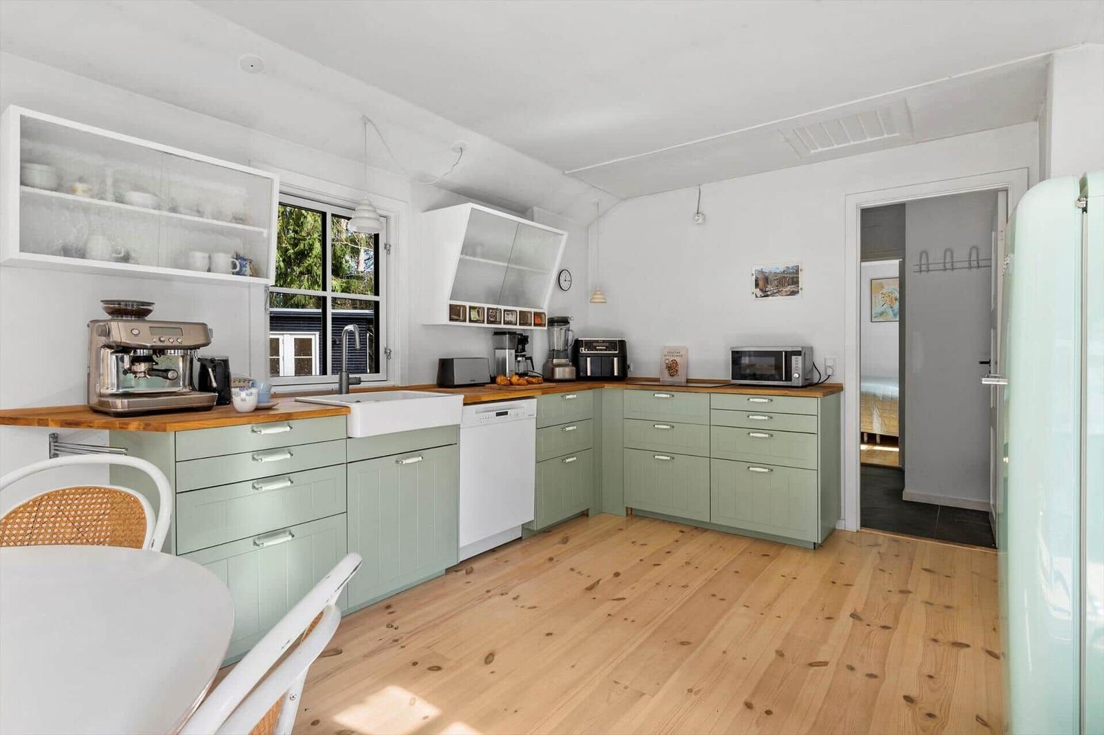 Kitchen with light green cabinets, wooden surfaces, and modern appliances.