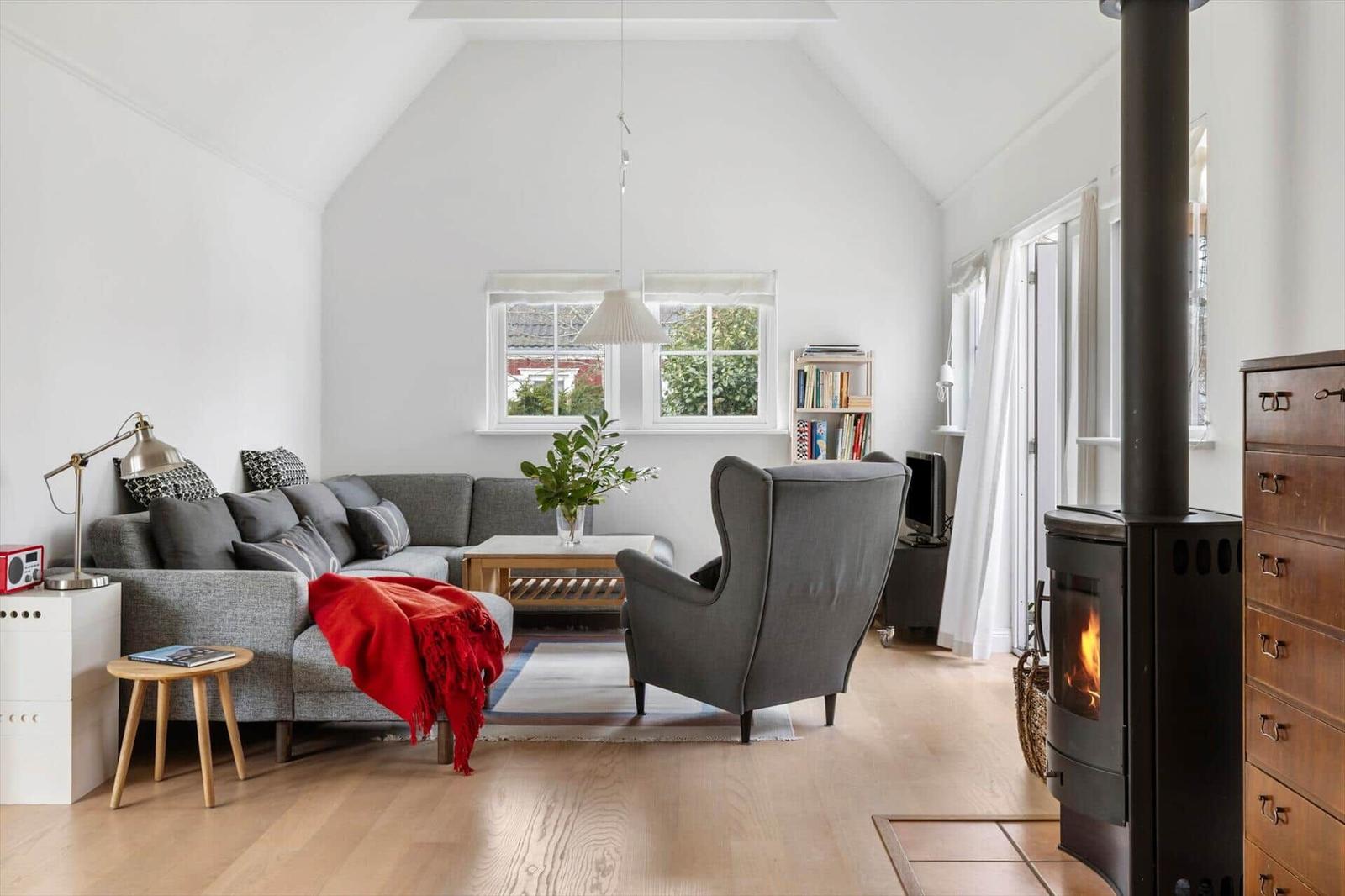 Living room with sofa, armchair, fireplace, and wooden floor.