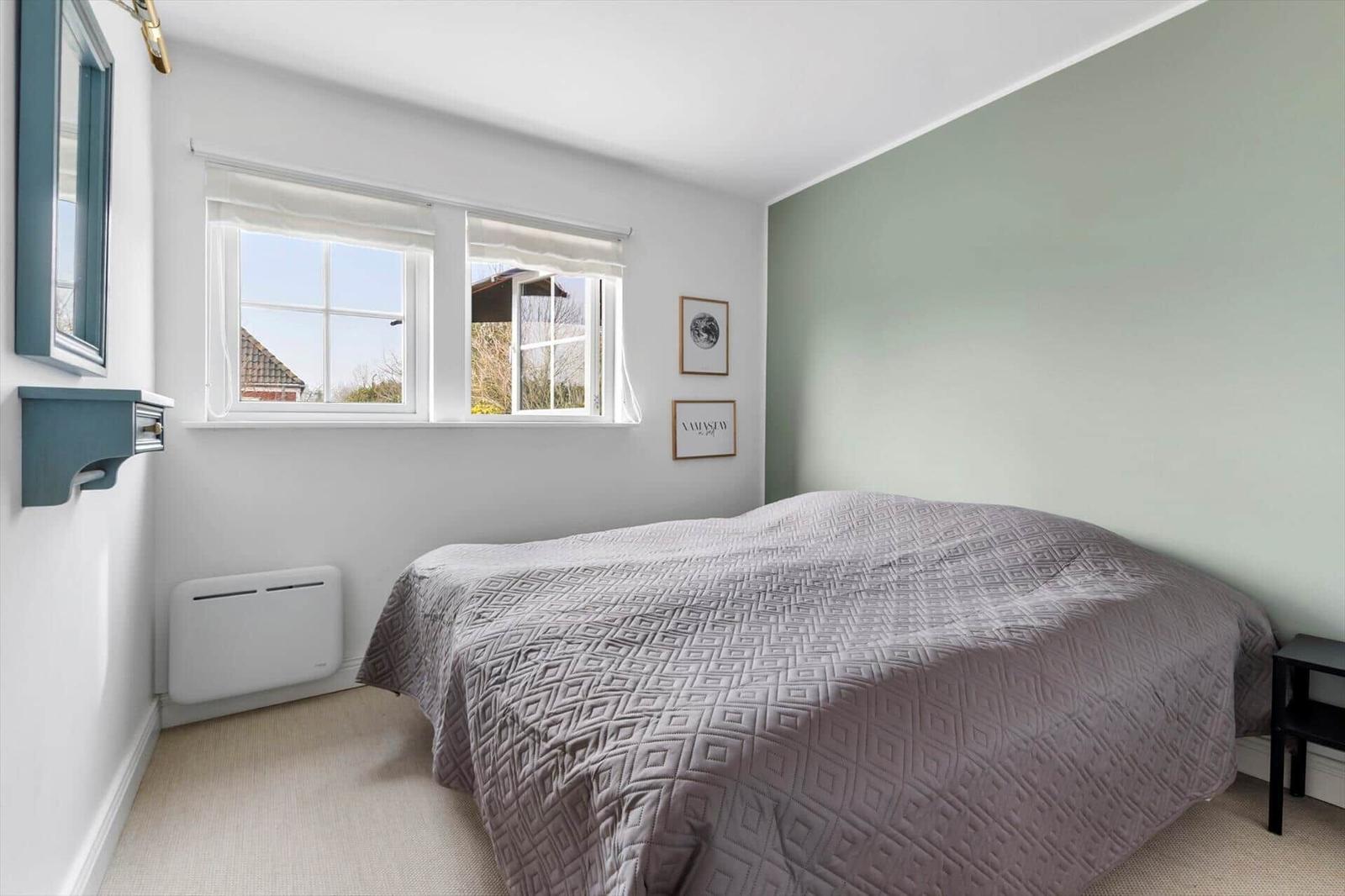 Bedroom with bed, window, and wall decor.