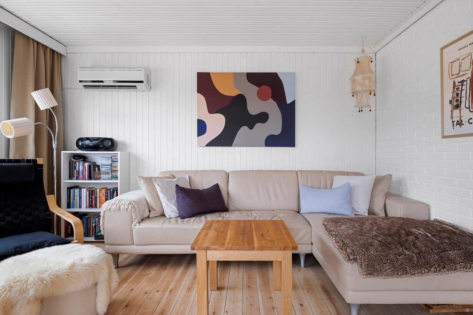 Living room with sofa, coffee table, and wall art. Wooden floor and white walls.