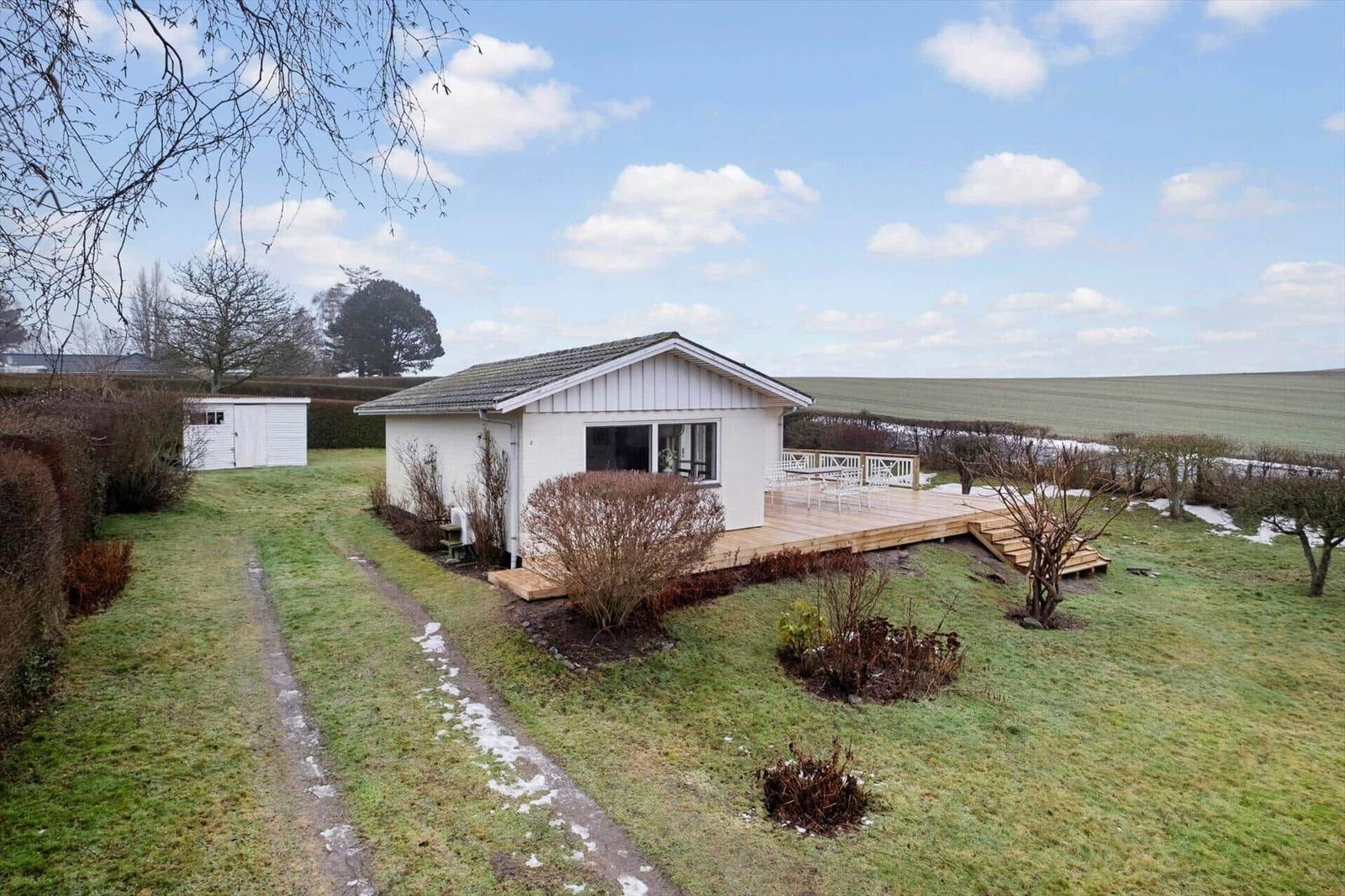 House with terrace, garden, and view of fields.