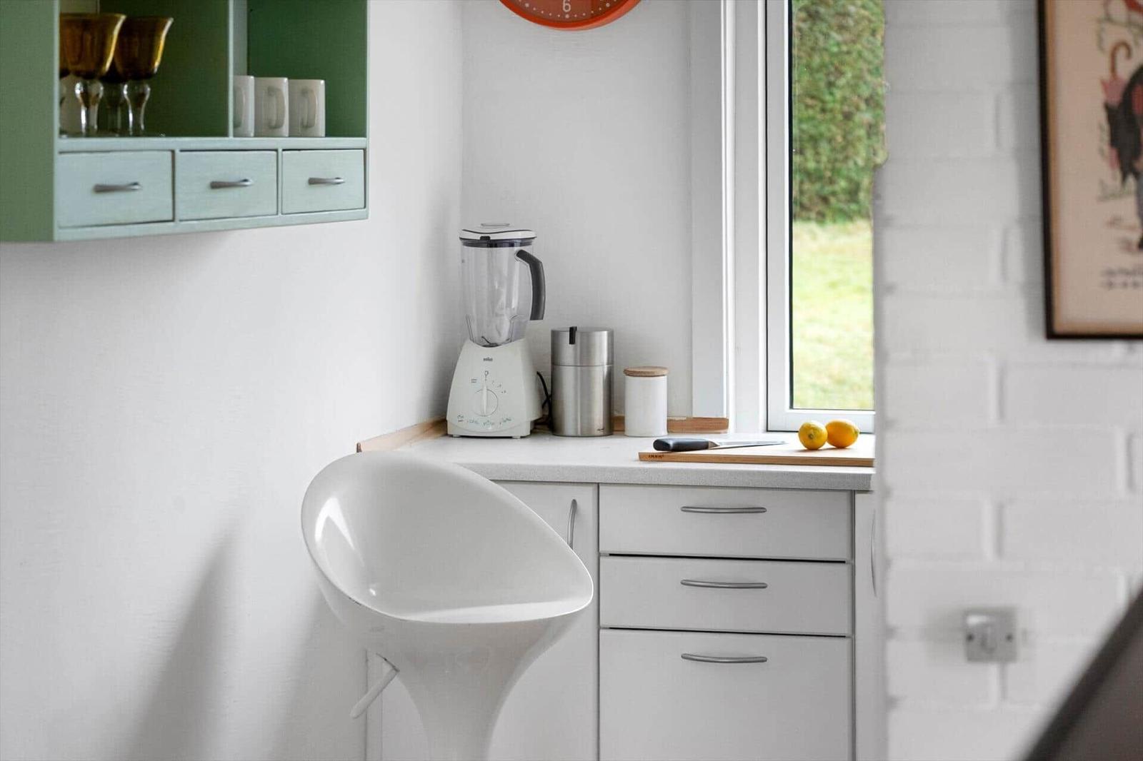 Kitchen area with white countertop, blender, and window view.