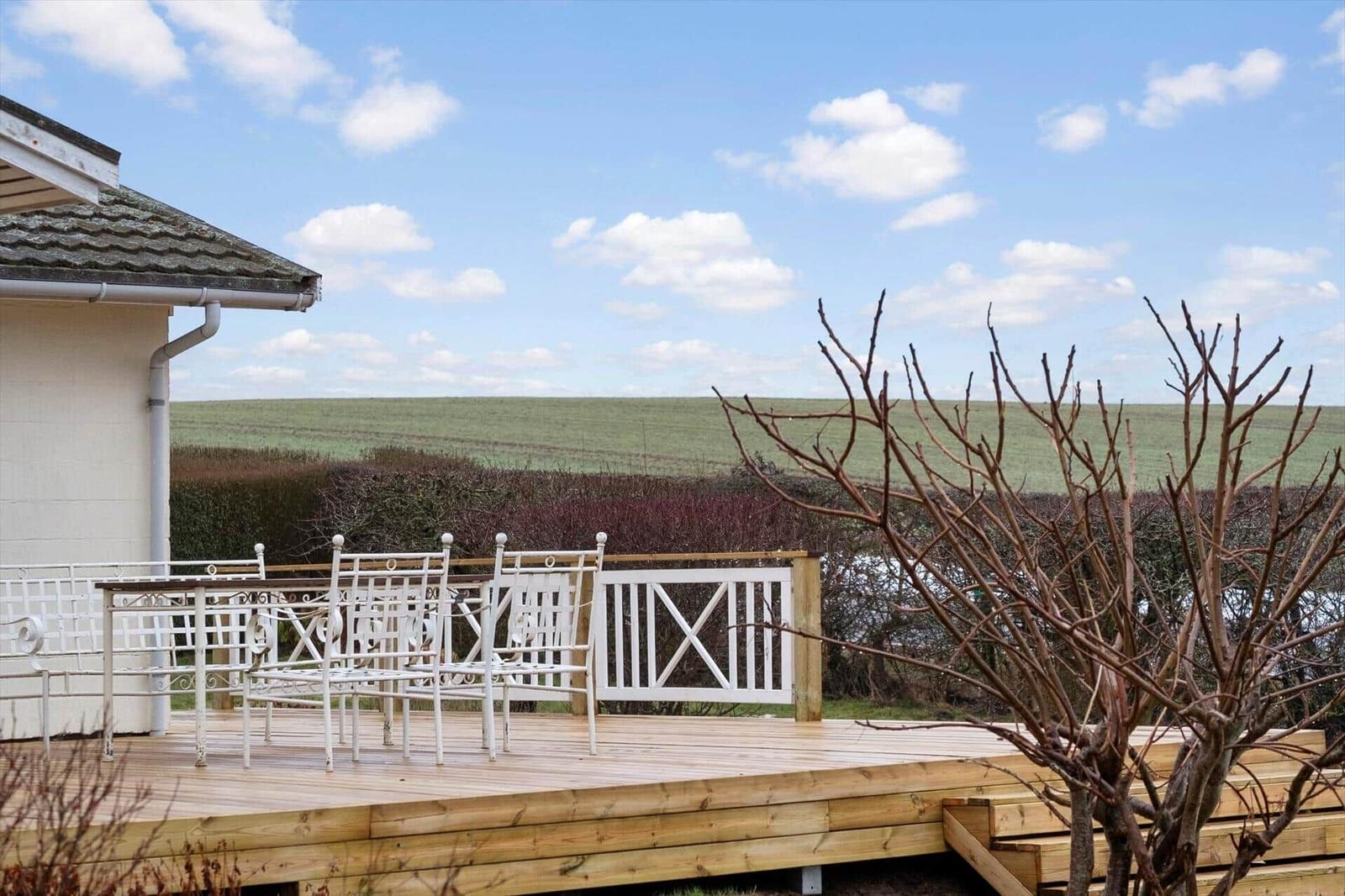 Deck with white garden furniture and view of fields.