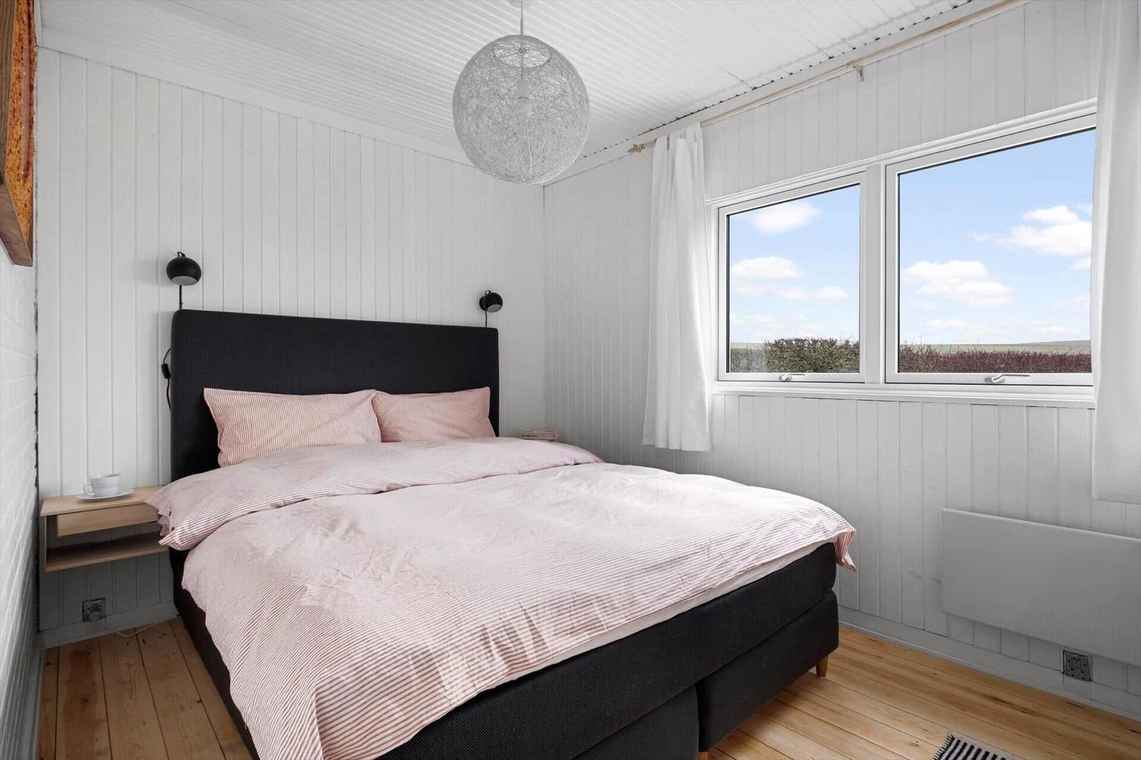 Bedroom with bed, windows, and ceiling light.