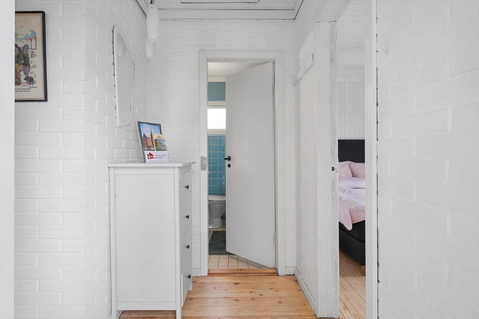 Hallway with white cabinet, bedroom, and bathroom with door handle.