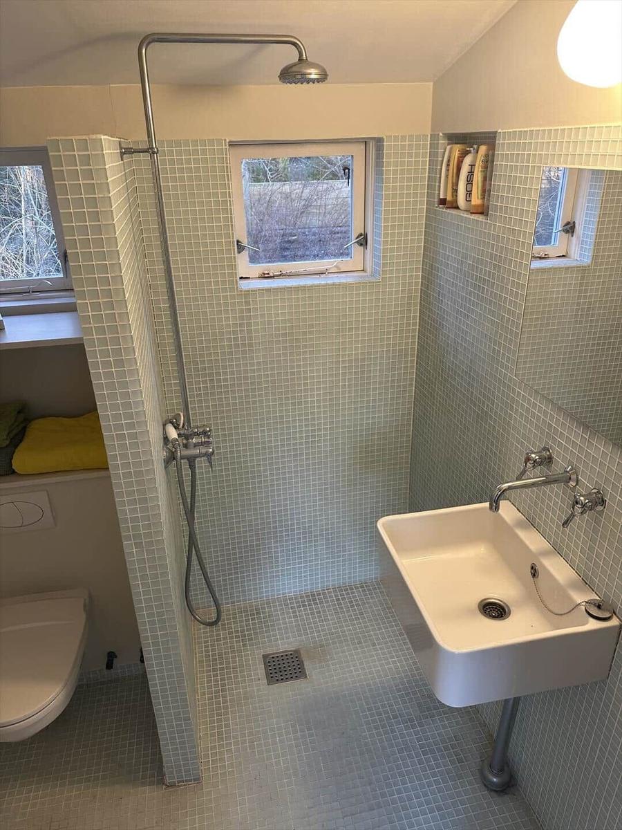 Shower with showerhead, sink, and toilet. Wall and floor tiles.