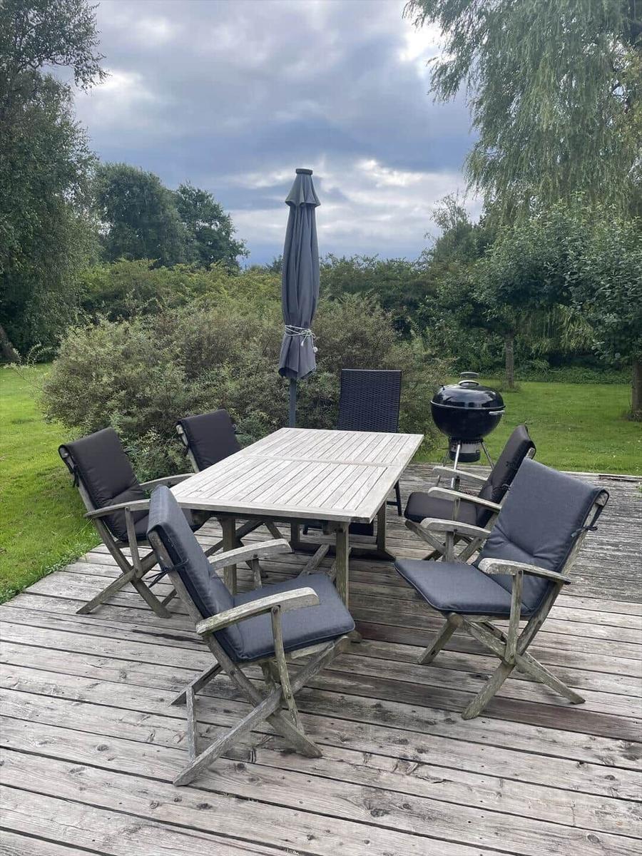 Deck with table, six chairs, umbrella, and grill.
