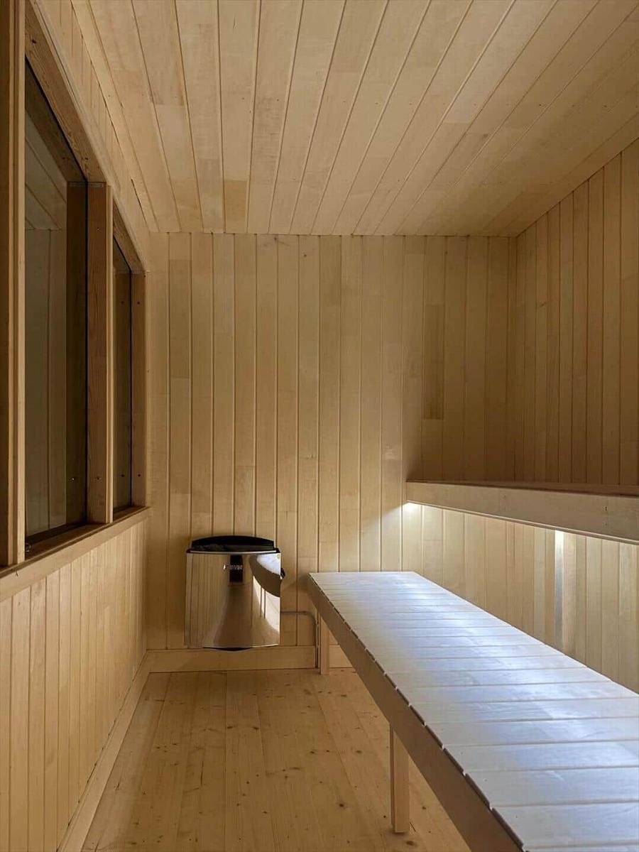 Sauna with wooden cladding, bench, and stove.