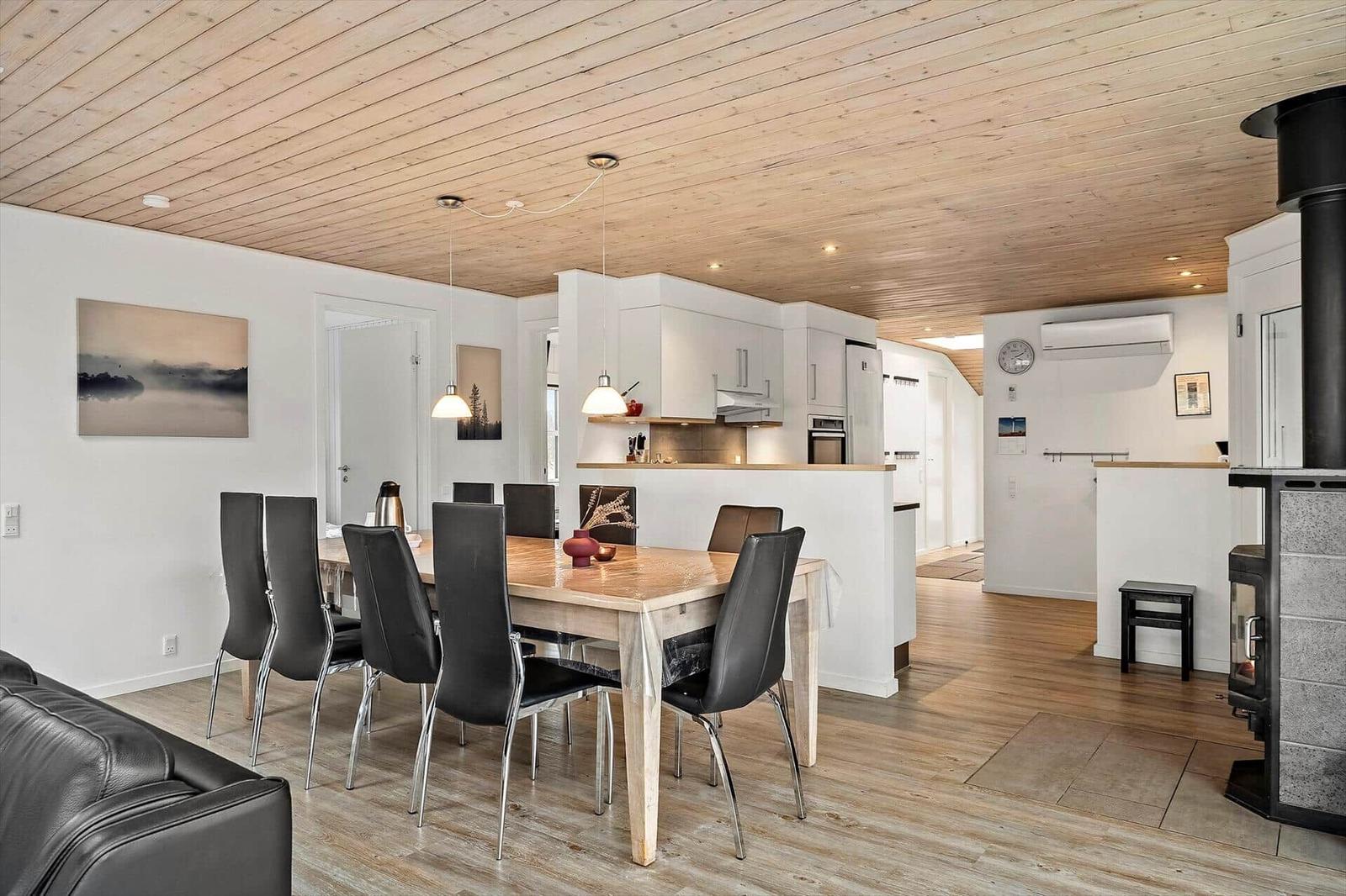 Essbereich mit Tisch, Stühlen und Küchenbereich unter Holzdecke.