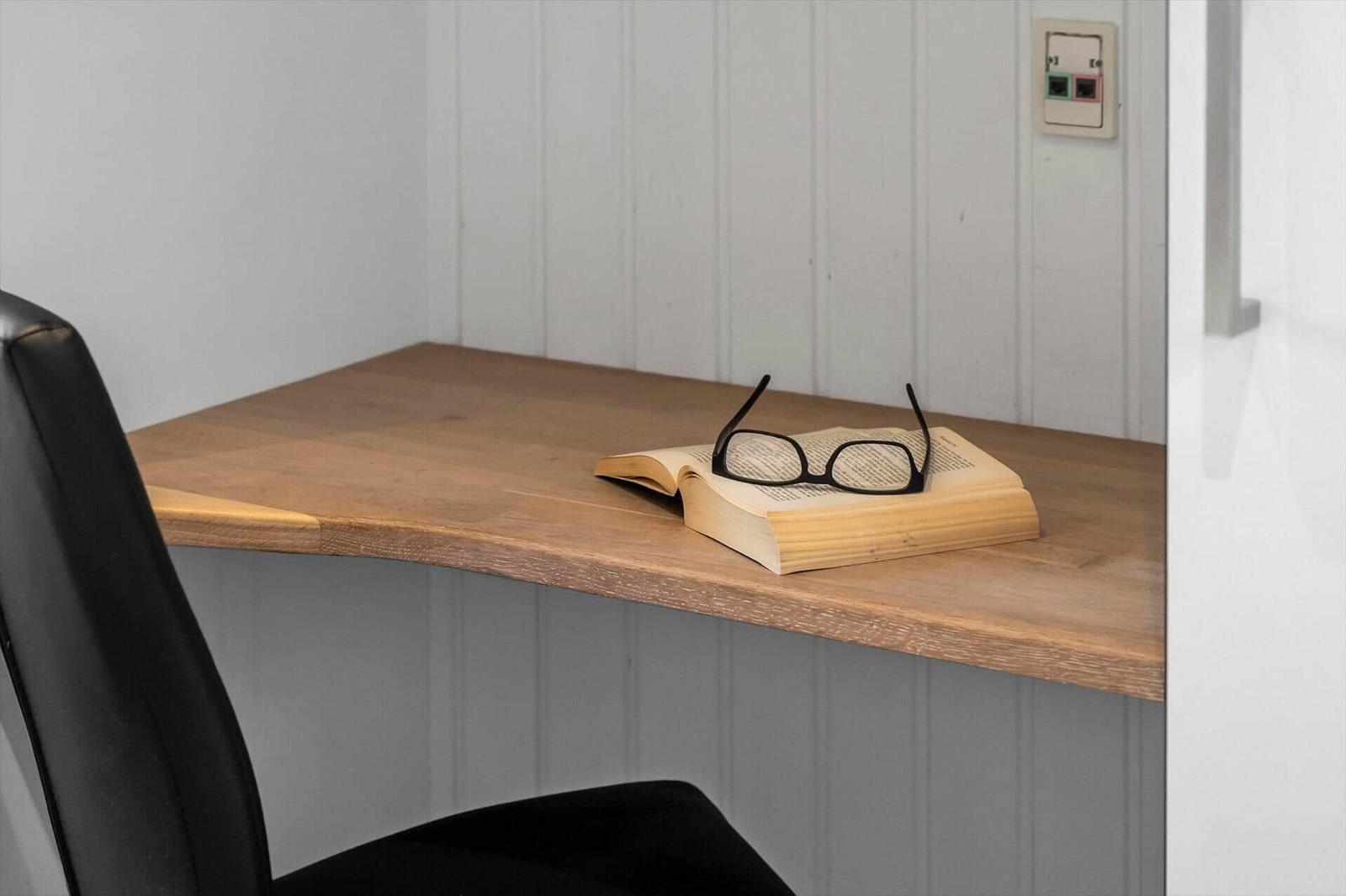 Schreibtisch mit Buch und Brille in Ecke