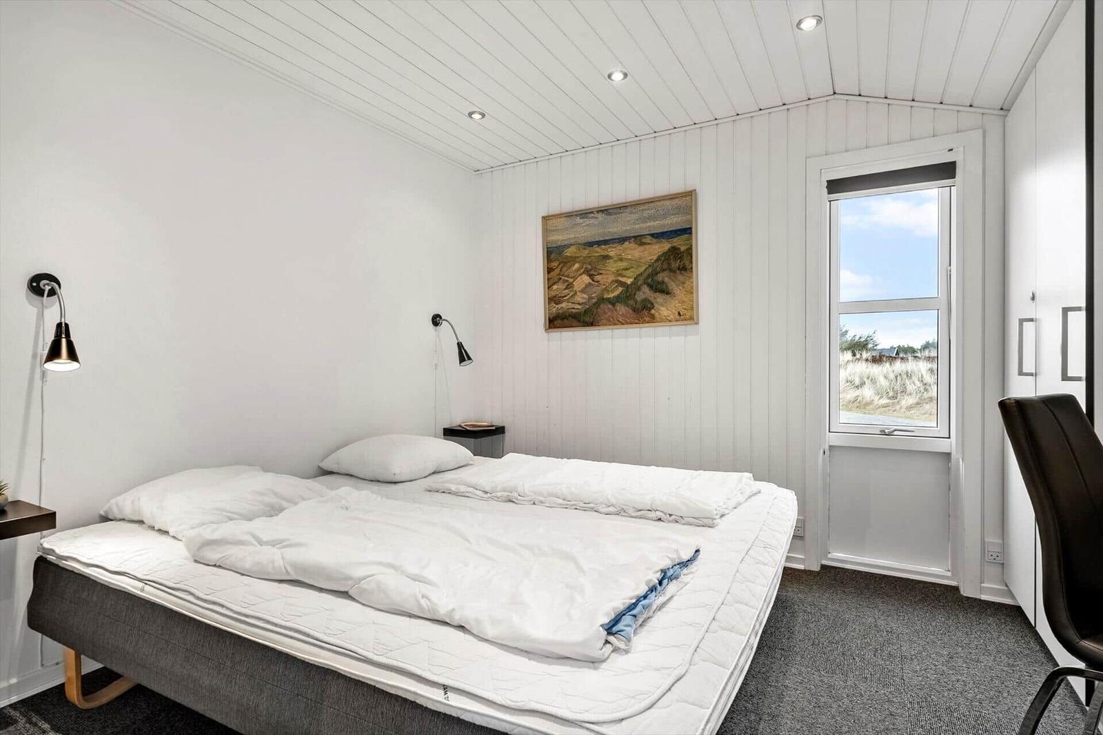 Schlafzimmer mit Bett, Fenster und Wandbild.