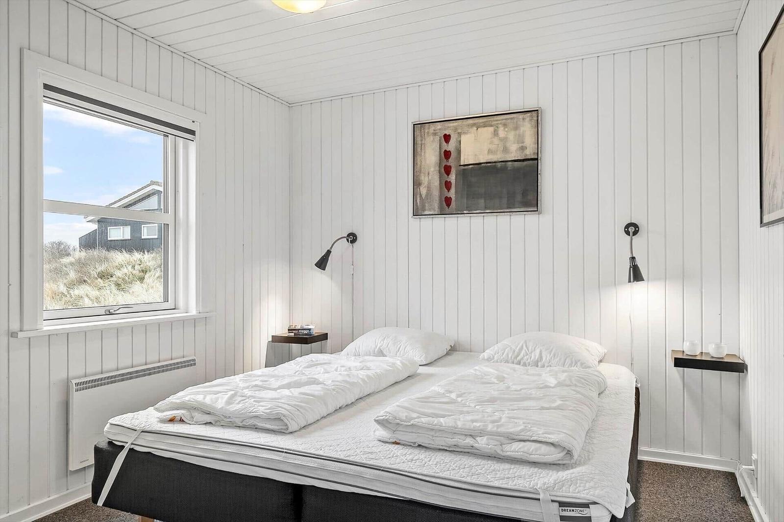 Schlafzimmer mit Doppelbett, Fenster und Wandbild.