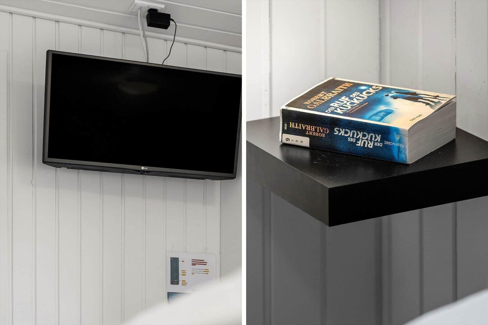 LG-TV an Wand montiert, Buch auf schwarzem Tisch