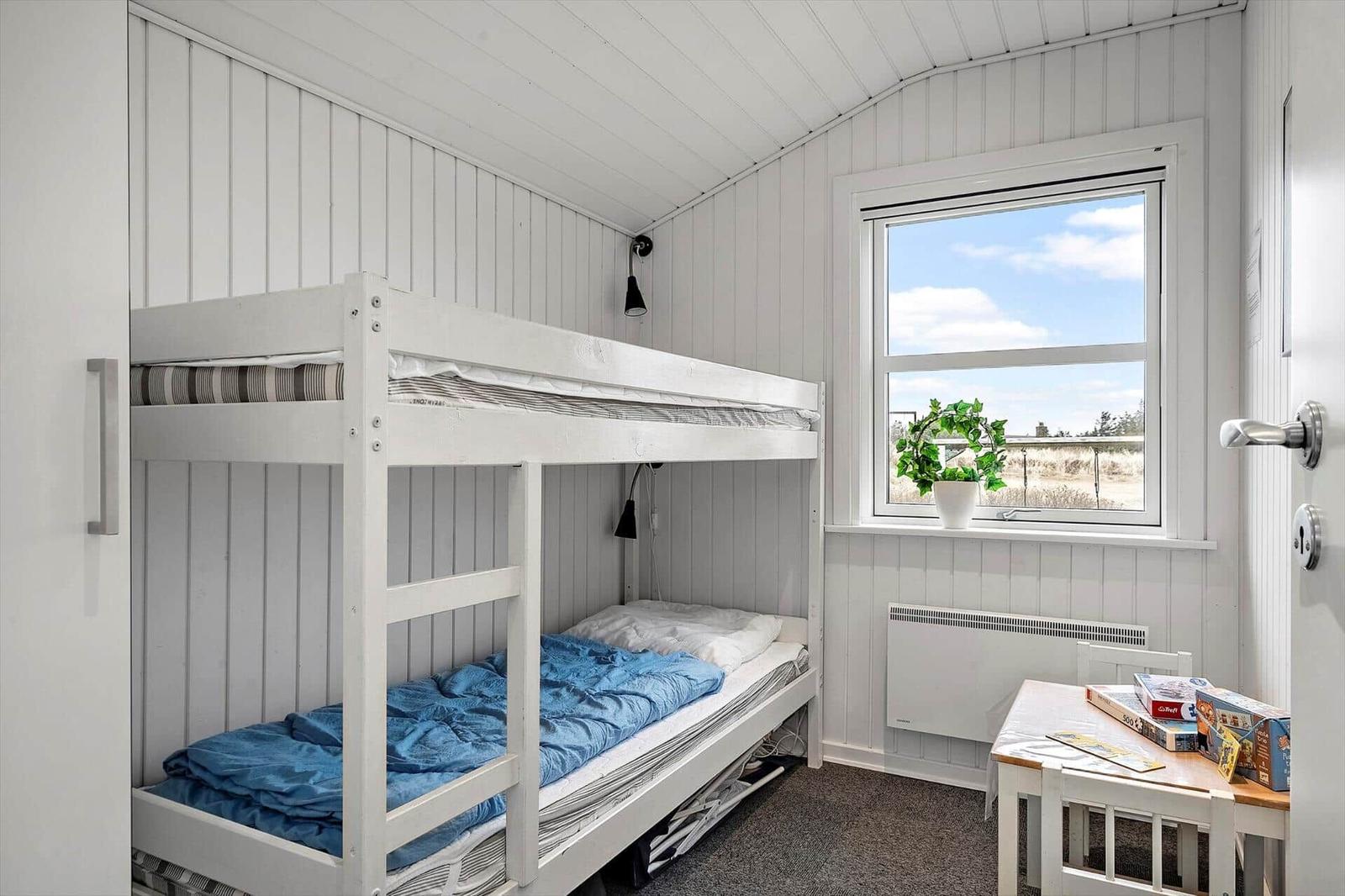 Zimmer mit Doppelstockbett, Fenster und Tisch.
