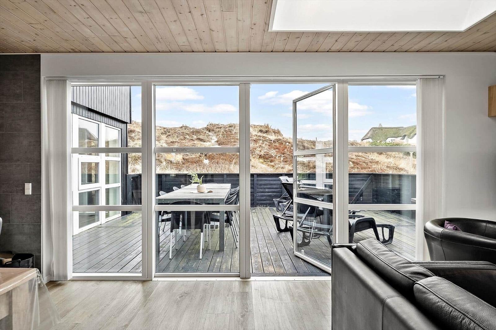 Große Fensterfront mit Blick auf Terrasse und Dünen.