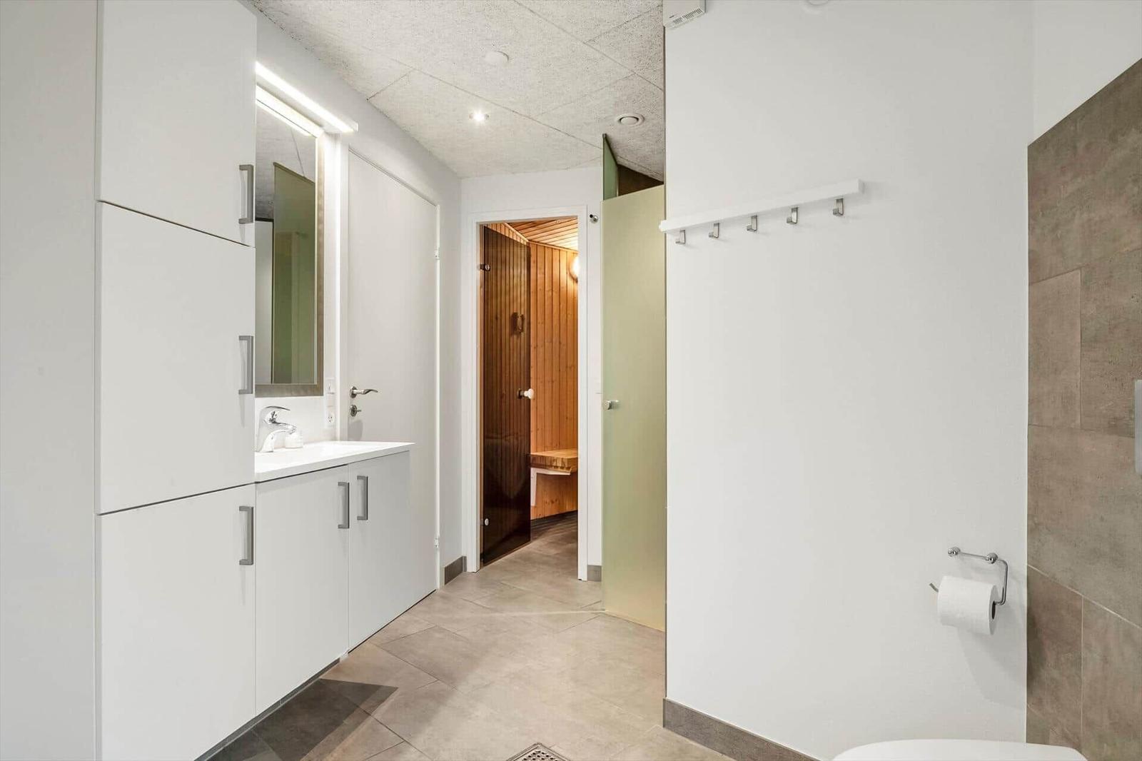 Flur mit Waschbecken, Spiegelschrank und Blick in Sauna.