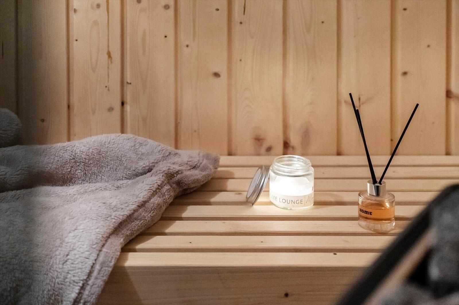 Holzbank mit Handtuch, Duftkerze und Duftdiffusor in Sauna.