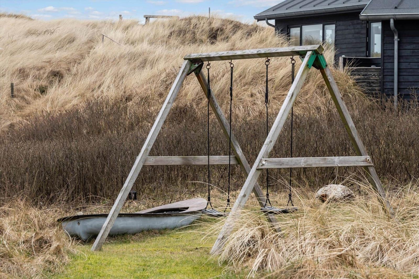 Schaukel im Gras vor einem Haus mit Dach und Fenstern.