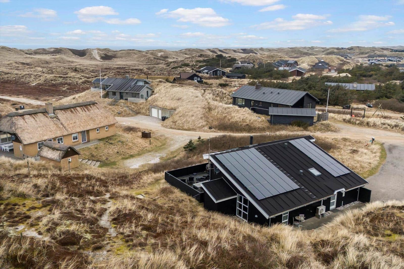 Dorf mit Häusern auf Dünen, einige mit Solaranlagen