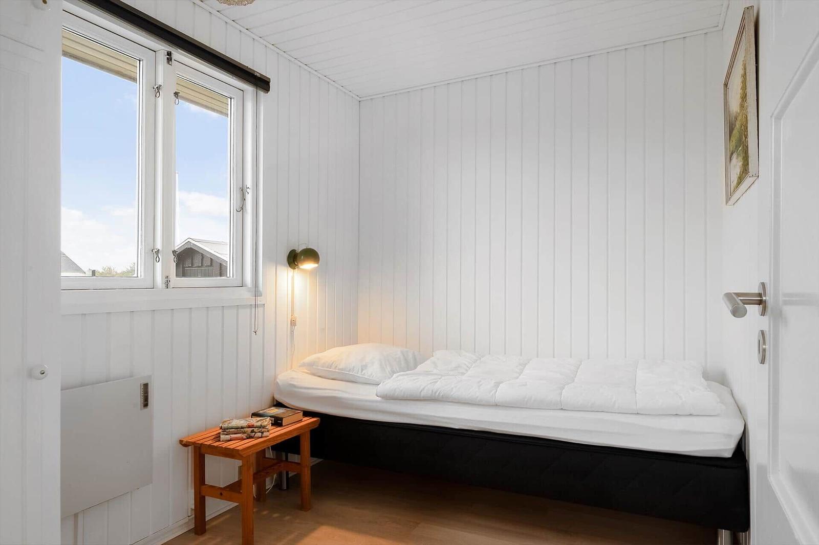 Schlafzimmer mit Bett, Fenster und Holztisch.