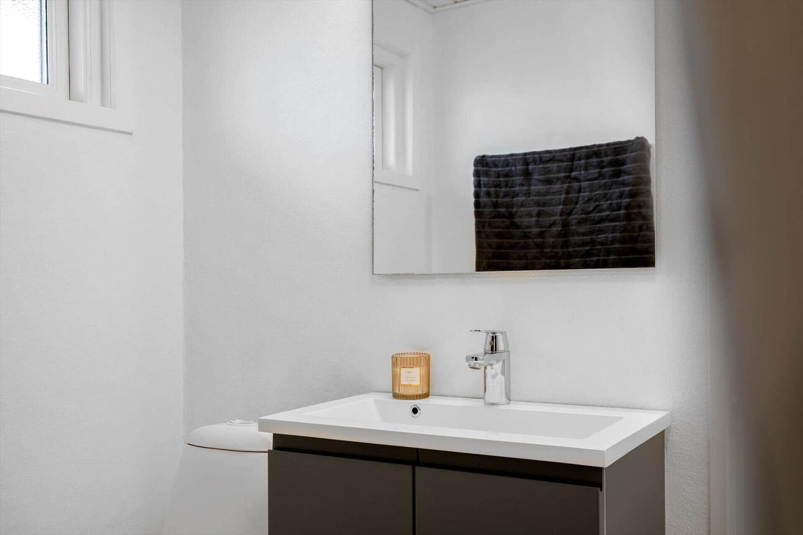 Badezimmer mit Waschbecken, Spiegel und Handtuch.