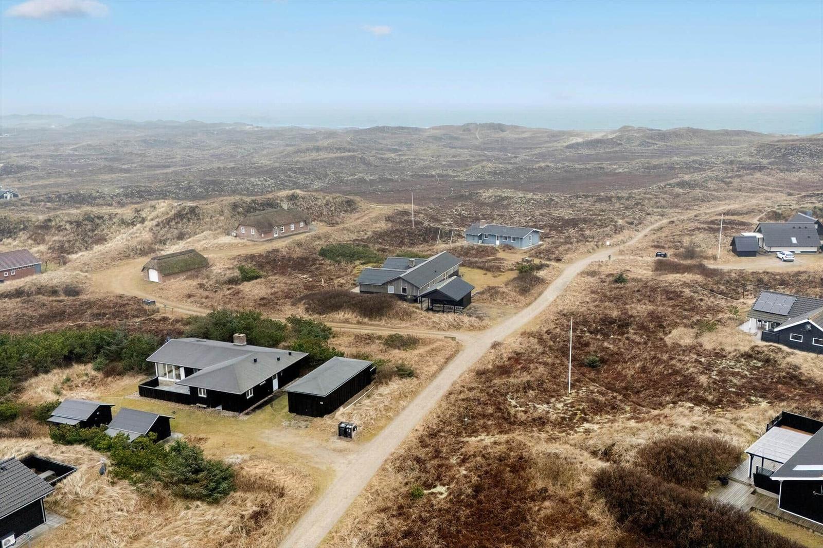 Aerial view of scattered houses on dunes near the sea.