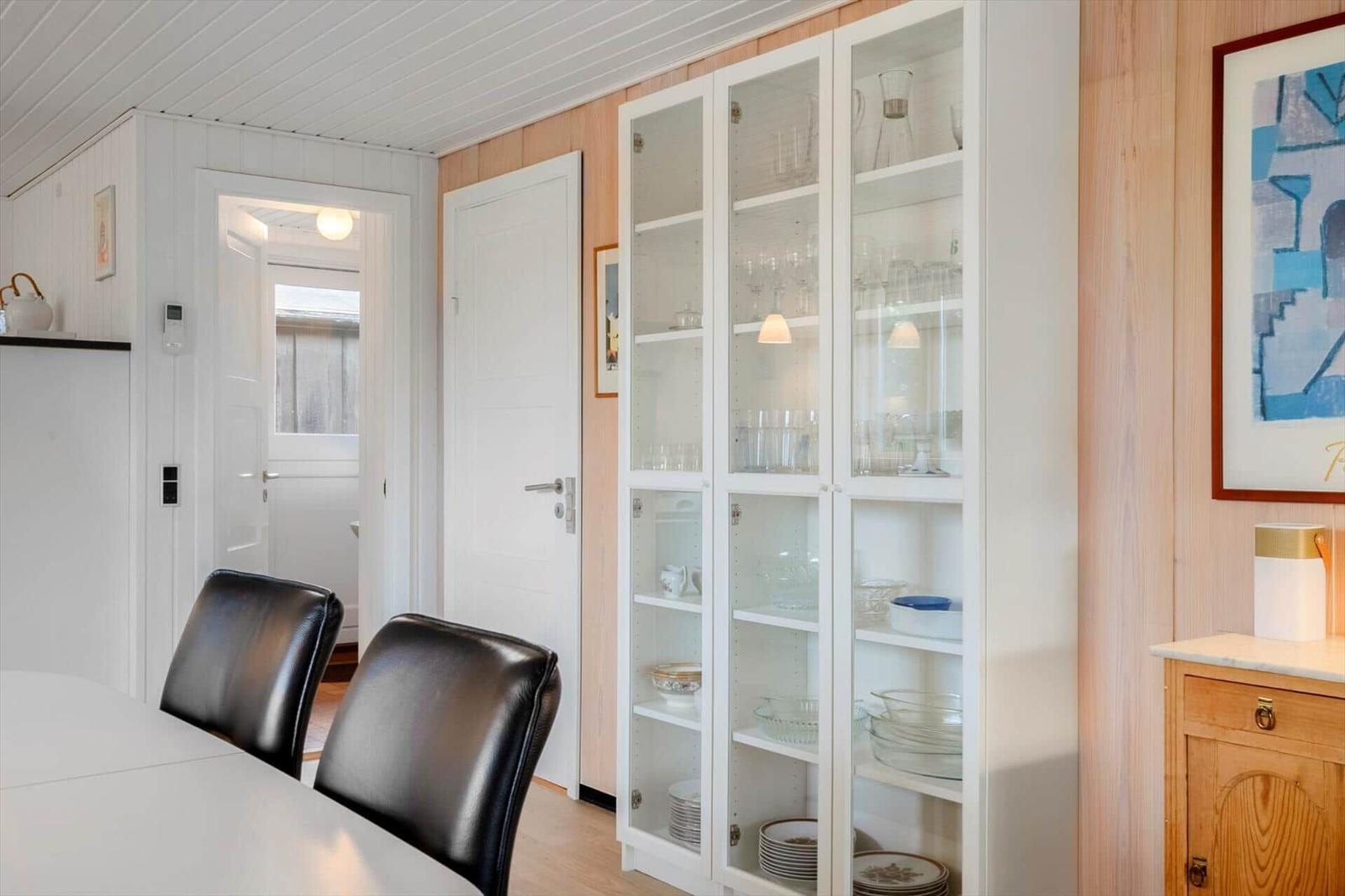 Esszimmer mit Glasvitrine, schwarzen Stühlen und Holzwand.